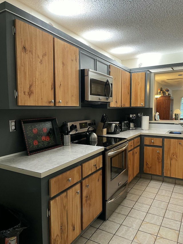 kitchen featuring sink, appliances with stainless steel finishes, light tile patterned flooring, and a textured ceiling