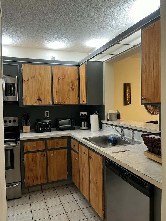 kitchen with light tile patterned flooring, stainless steel appliances, a textured ceiling, and sink