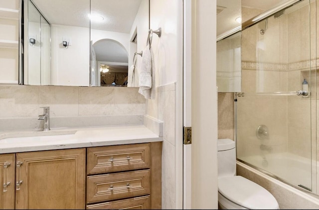 full bathroom featuring vanity, toilet, enclosed tub / shower combo, and backsplash