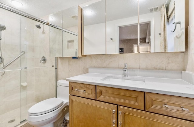 bathroom with vanity, decorative backsplash, toilet, tile walls, and a shower with shower door