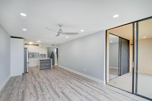 unfurnished living room featuring ceiling fan and light wood-type flooring