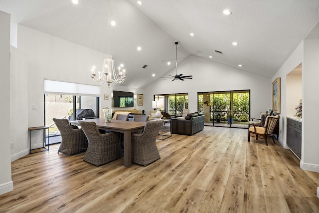 dining area featuring ceiling fan with notable chandelier, light hardwood / wood-style flooring, and high vaulted ceiling