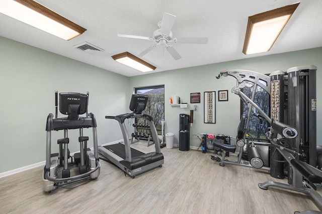 exercise area with ceiling fan, a textured ceiling, and light wood-type flooring