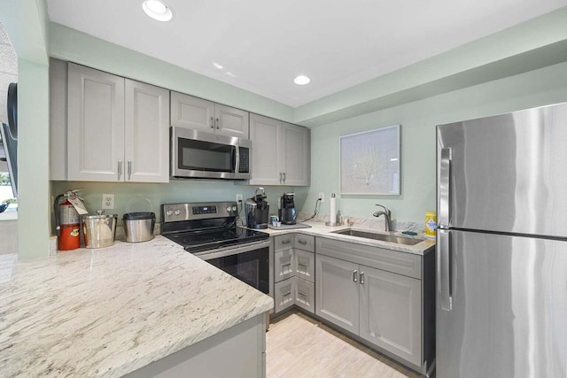 kitchen featuring light stone countertops, sink, gray cabinetry, and stainless steel appliances