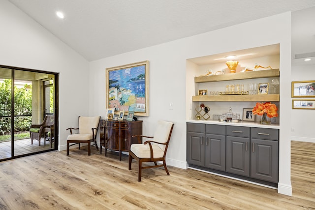 bar with vaulted ceiling, light hardwood / wood-style floors, and gray cabinets