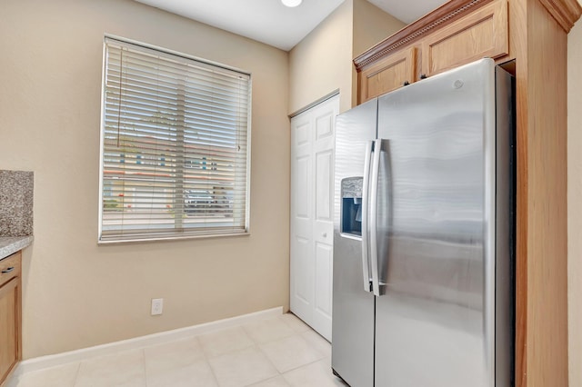 kitchen featuring stainless steel refrigerator with ice dispenser, light brown cabinetry, and light tile patterned floors