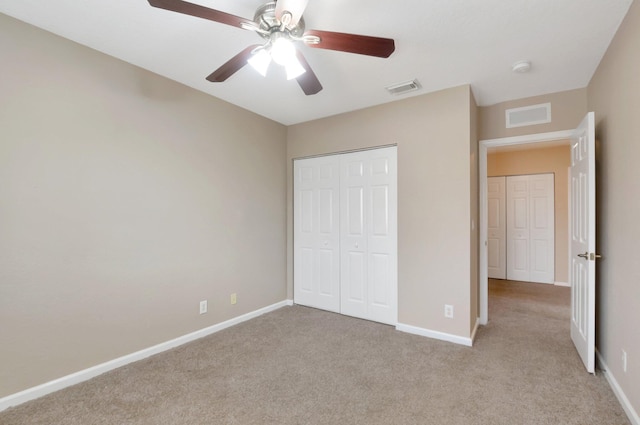 unfurnished bedroom featuring ceiling fan, light colored carpet, and a closet