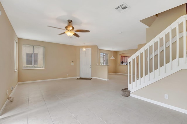 unfurnished room featuring light tile patterned flooring and ceiling fan with notable chandelier