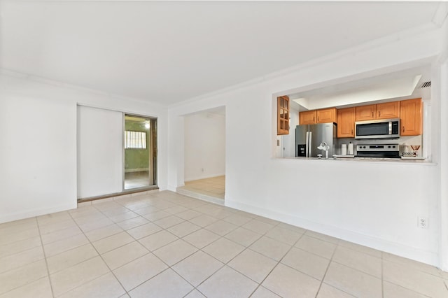 kitchen featuring brown cabinets, light tile patterned floors, light countertops, appliances with stainless steel finishes, and baseboards