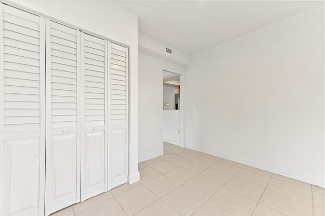 unfurnished bedroom with a closet, visible vents, baseboards, and light tile patterned floors