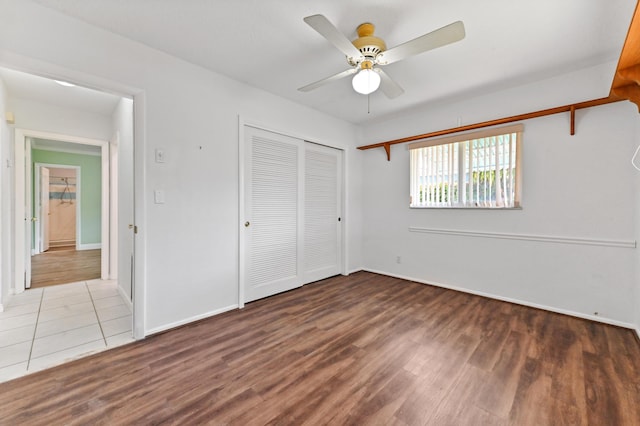 unfurnished bedroom featuring a ceiling fan, a closet, baseboards, and wood finished floors