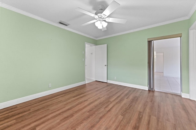 unfurnished bedroom with wood finished floors, a ceiling fan, visible vents, baseboards, and ornamental molding