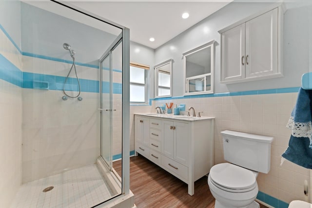 full bathroom with toilet, a shower stall, tile walls, and wood finished floors