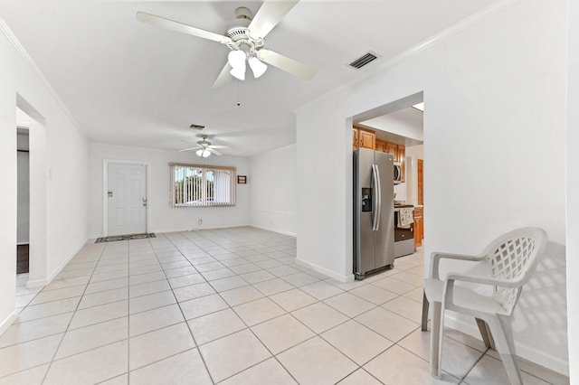 spare room featuring crown molding, light tile patterned floors, visible vents, a ceiling fan, and baseboards