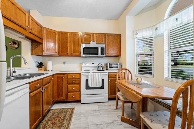 kitchen featuring a textured ceiling, sink, and white appliances