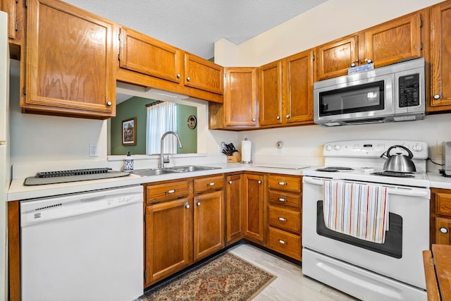 kitchen featuring a textured ceiling, sink, and white appliances