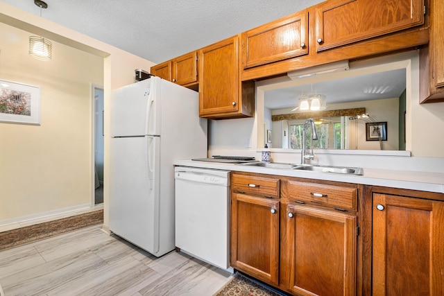 kitchen with decorative light fixtures, sink, white appliances, and a textured ceiling