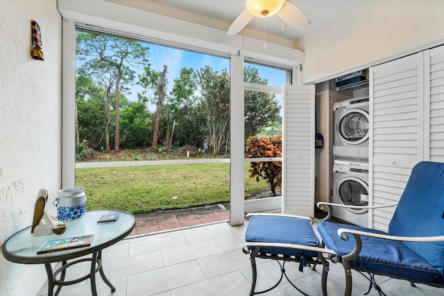 sunroom featuring ceiling fan and stacked washer and clothes dryer