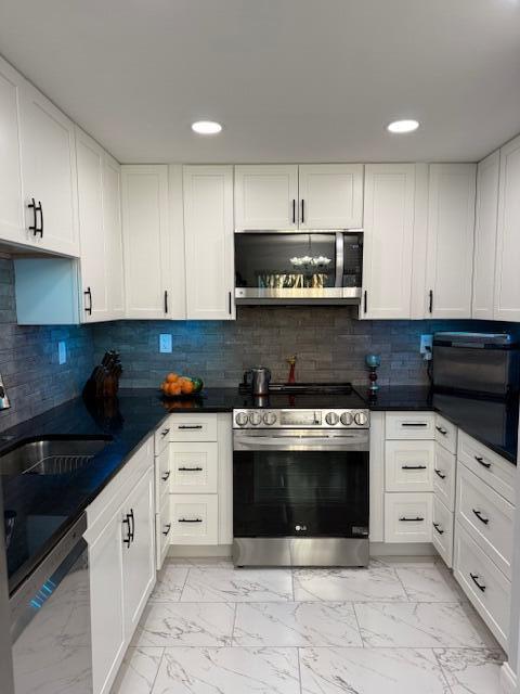 kitchen with sink, white cabinets, decorative backsplash, and appliances with stainless steel finishes