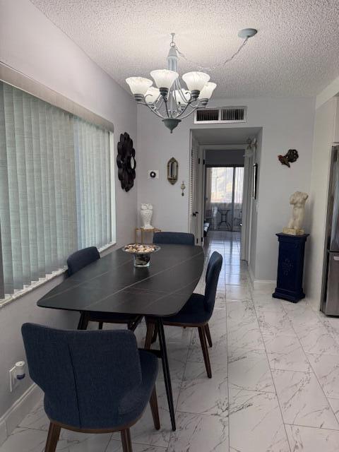 dining space featuring an inviting chandelier and a textured ceiling