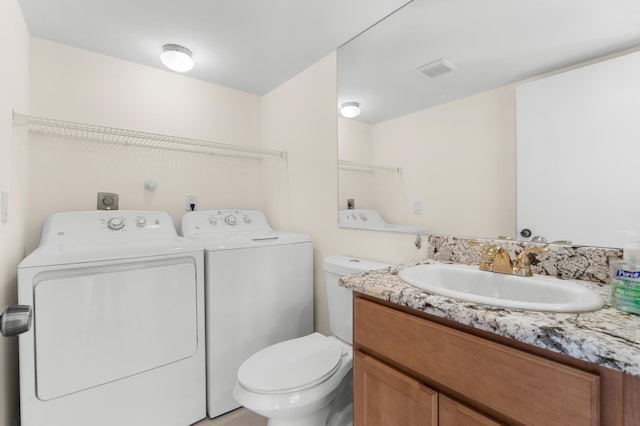 bathroom featuring washing machine and dryer, vanity, and toilet