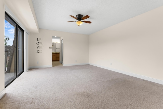 spare room with ceiling fan, light colored carpet, and a textured ceiling