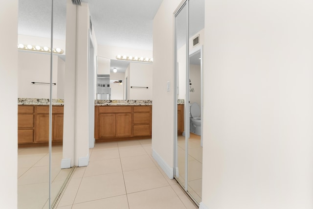 hallway featuring sink, a textured ceiling, and light tile patterned flooring