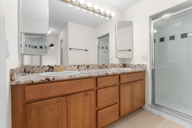 bathroom with a shower with door, vanity, a textured ceiling, and tile patterned flooring