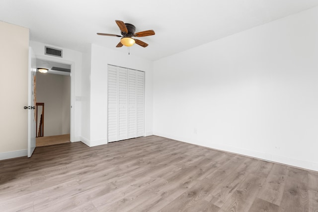 unfurnished bedroom with ceiling fan, light wood-type flooring, and a closet