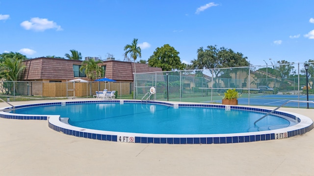 view of swimming pool with tennis court