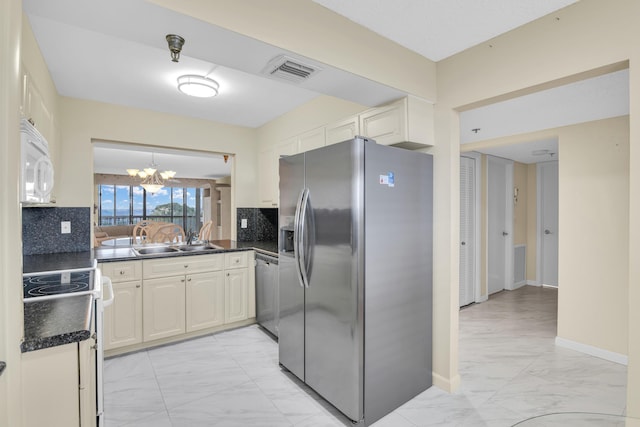 kitchen with sink, backsplash, stainless steel appliances, and a chandelier