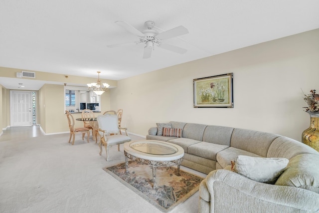 carpeted living room with ceiling fan with notable chandelier