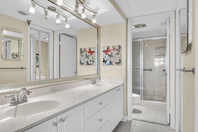 bathroom featuring toilet, tile patterned floors, a shower with shower door, and vanity