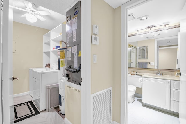 bathroom featuring a textured ceiling, washer / dryer, vanity, toilet, and ceiling fan