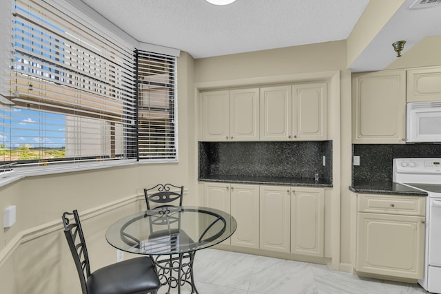 kitchen with white appliances, a textured ceiling, cream cabinets, and tasteful backsplash