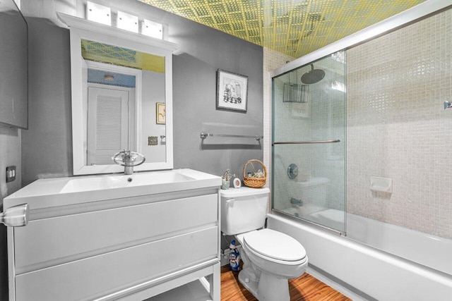 full bathroom with shower / bath combination with glass door, hardwood / wood-style floors, vanity, and toilet