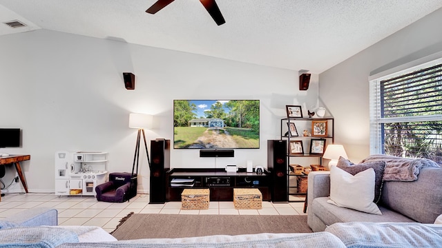 home theater featuring ceiling fan, light tile patterned floors, vaulted ceiling, and a textured ceiling