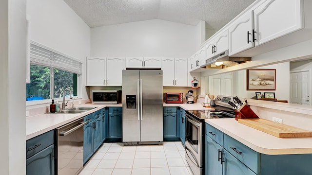 kitchen featuring white cabinets, appliances with stainless steel finishes, blue cabinetry, and vaulted ceiling