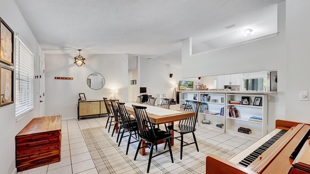 tiled dining space featuring vaulted ceiling and a textured ceiling