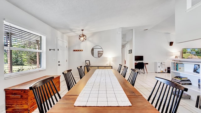 tiled dining space featuring lofted ceiling, an inviting chandelier, and a textured ceiling