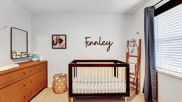 bedroom with light carpet, a nursery area, and multiple windows