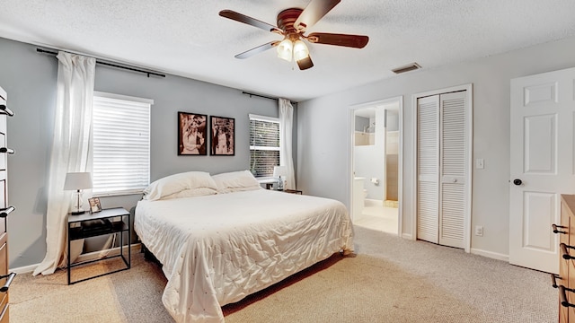 carpeted bedroom featuring ceiling fan, a textured ceiling, ensuite bathroom, and a closet