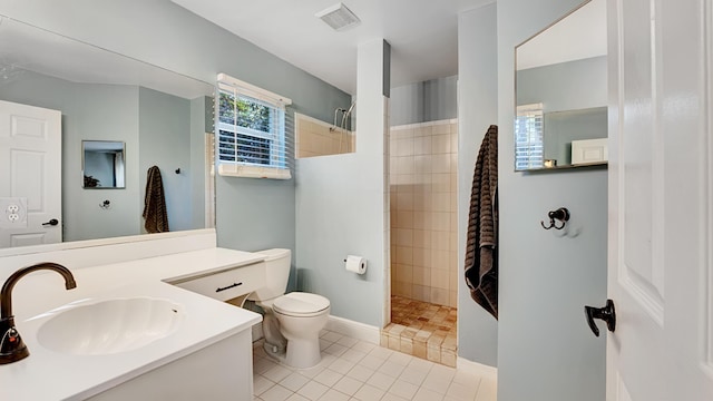 bathroom featuring tile patterned floors, vanity, a tile shower, and toilet