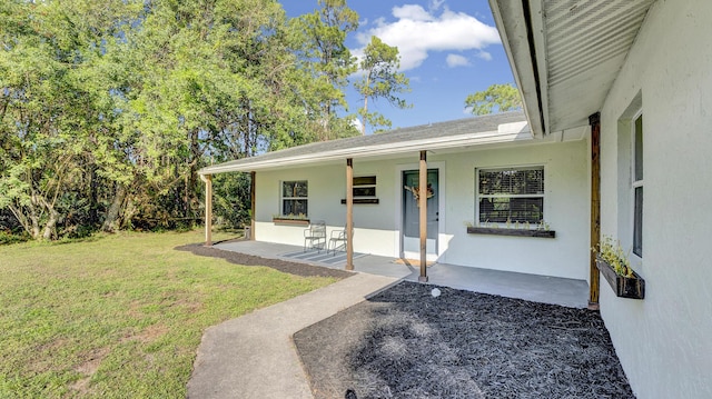 entrance to property featuring a patio area and a yard