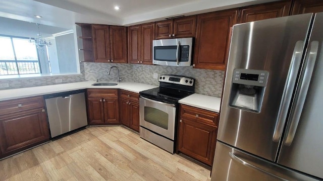 kitchen featuring appliances with stainless steel finishes, tasteful backsplash, light wood-type flooring, a chandelier, and sink