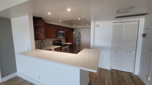 kitchen featuring sink, appliances with stainless steel finishes, dark hardwood / wood-style floors, and kitchen peninsula