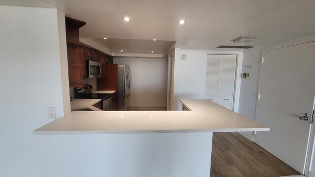 kitchen featuring stainless steel appliances, backsplash, kitchen peninsula, and a breakfast bar