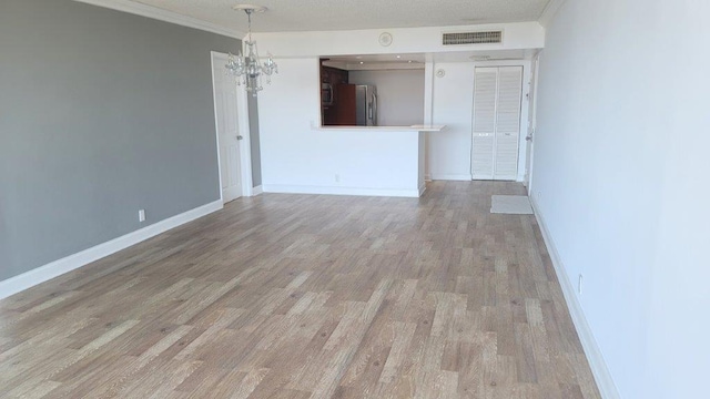 unfurnished living room with a chandelier, crown molding, and light hardwood / wood-style floors