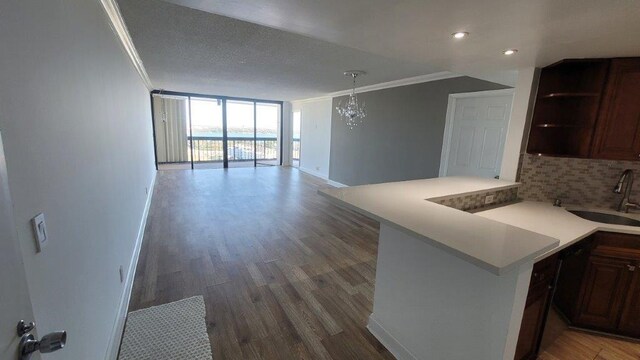 kitchen featuring sink, crown molding, a wall of windows, and kitchen peninsula