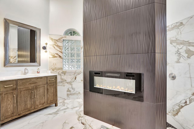 bathroom featuring a lit fireplace, marble finish floor, vanity, and tile walls